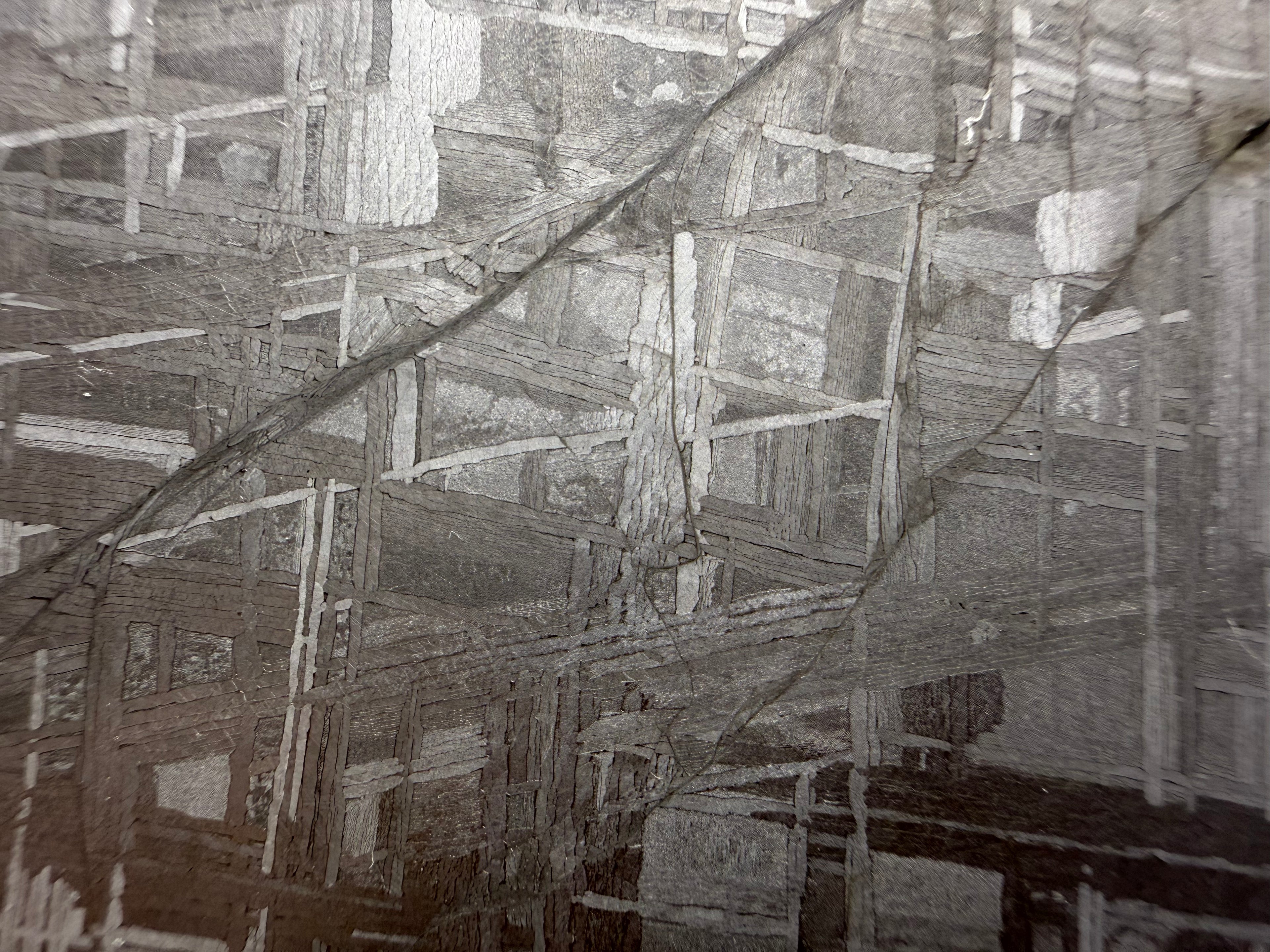 Shock deformation vein visible across the Widmanstätten structure of a Muonionalusta iron meteorite slice.