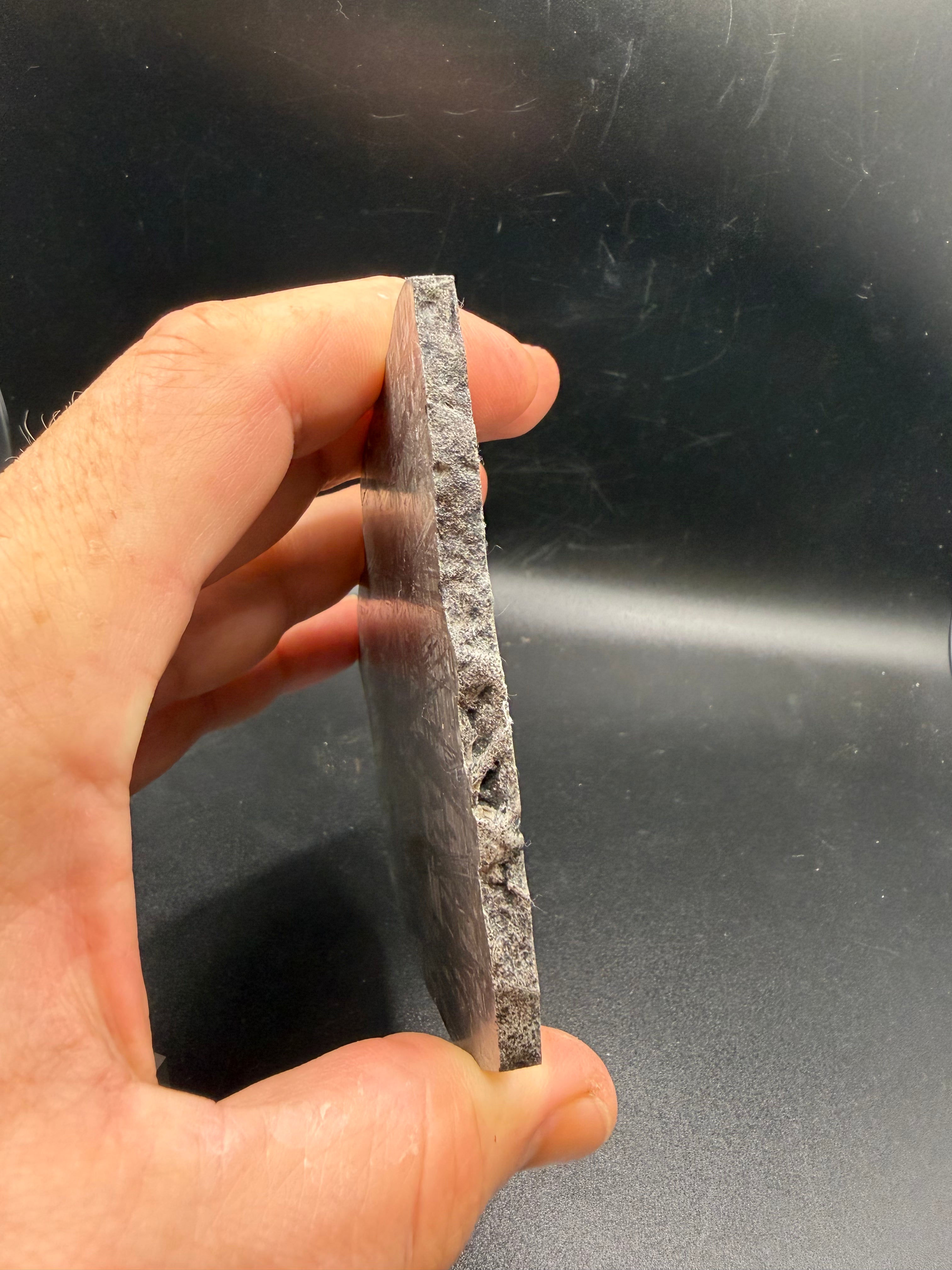 Edge profile of Muonionalusta iron meteorite slice revealing thickness and crystalline metal structure.