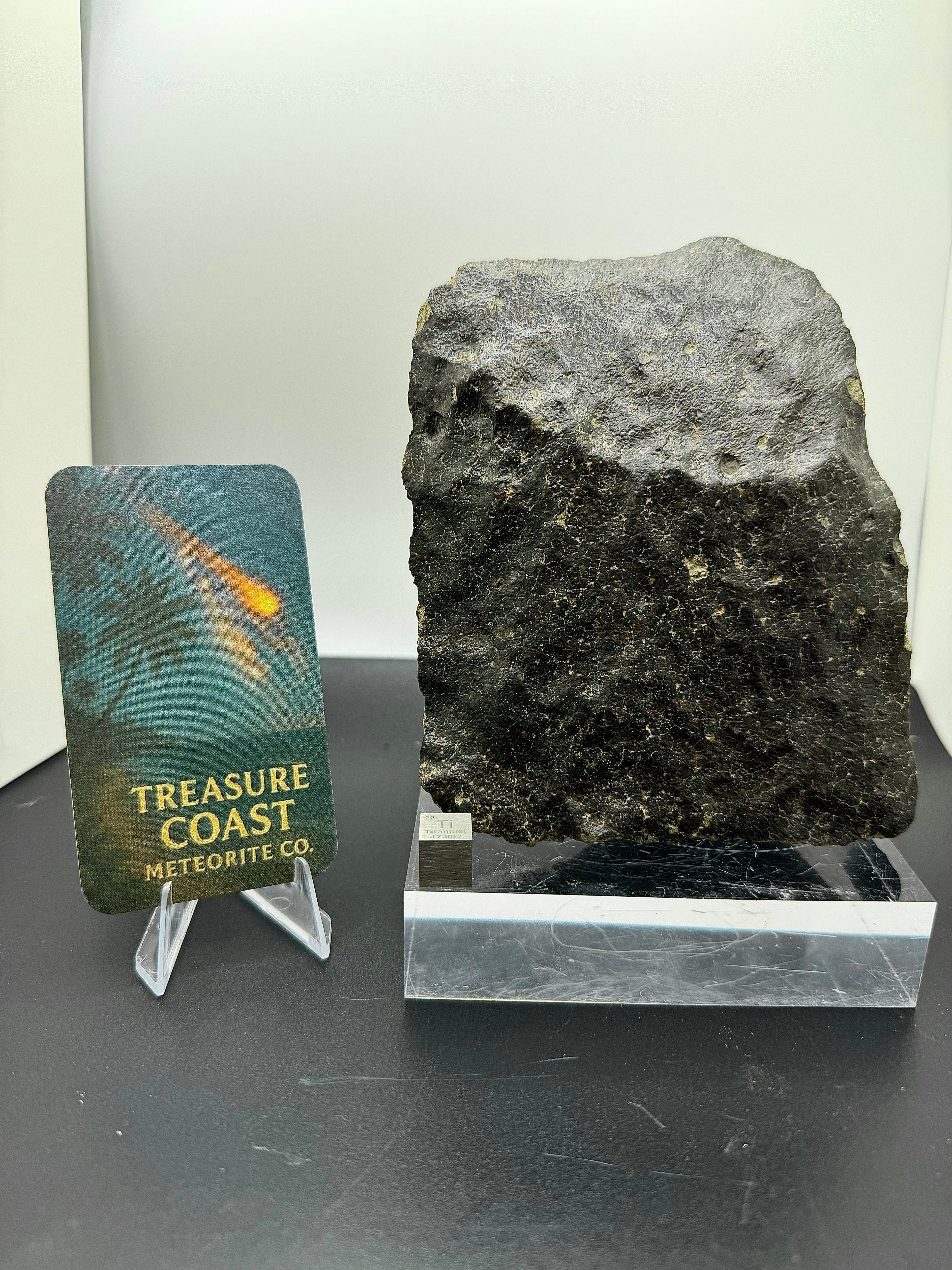 Display photo of NWA 17296 L5 Ordinary Chondrite Meteorite showing oriented complete individual with black fusion crust and regmaglypt depressions, 1472.00g