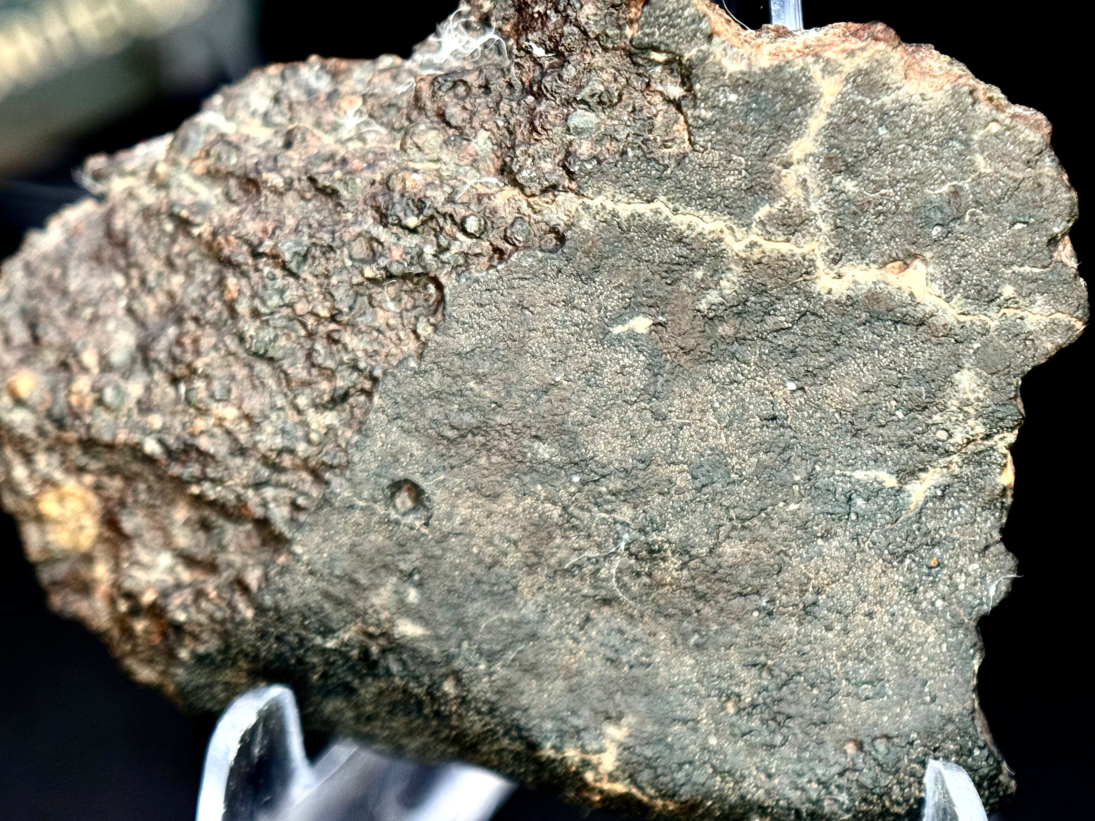 Macro photo of NWA 17364 LL3.10 chondrite showing fusion crust exterior with rippled atmospheric entry flow texture - 13.34g