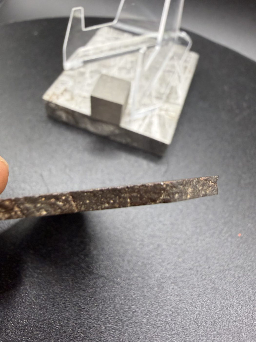 Edge profile of NWA 17916 CO3 carbonaceous chondrite meteorite slice held in hand showing slice thickness, 11.28g