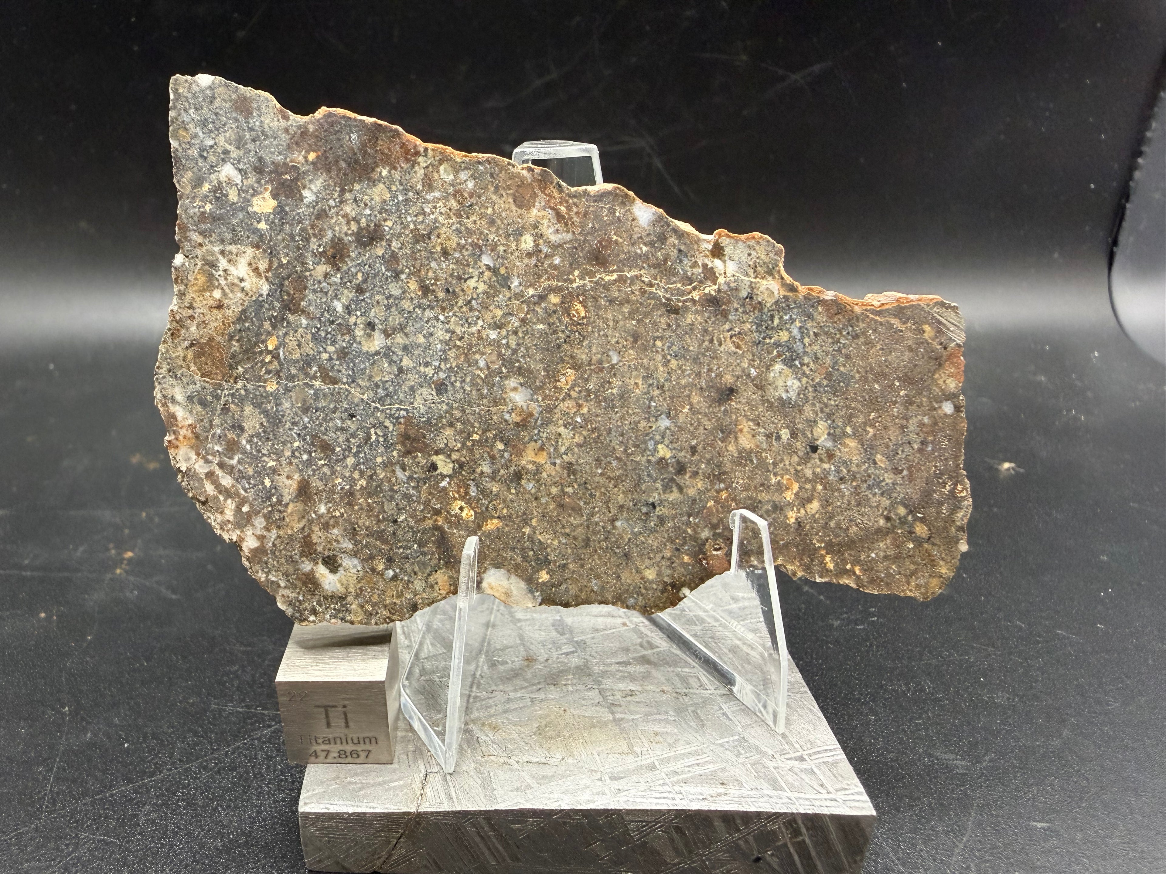33.79 g NWA 18452 eucrite breccia meteorite slice from Morocco displayed on stand