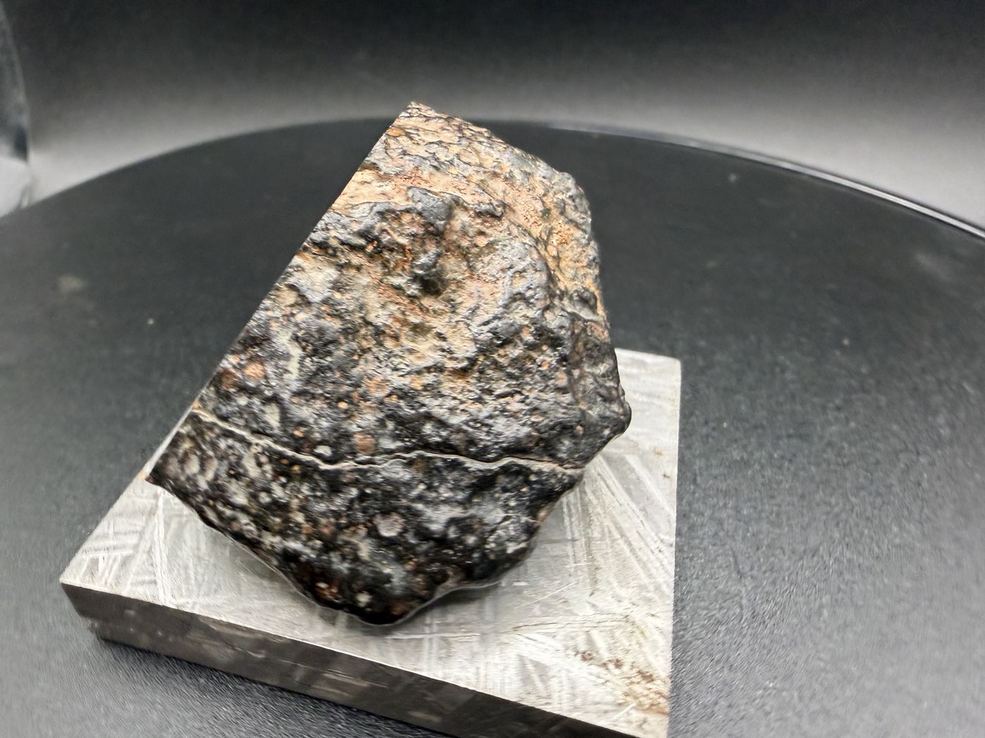 Side profile of NWA 18497 CVox3 carbonaceous chondrite end cut showing the natural weathered exterior