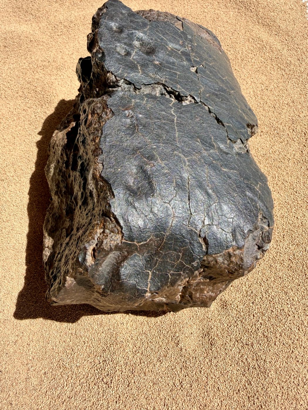 Full view of the NWA 18501 LL6 ordinary chondrite individual showing the crusted face, regmaglypts and weathered desert rind, 6183g.