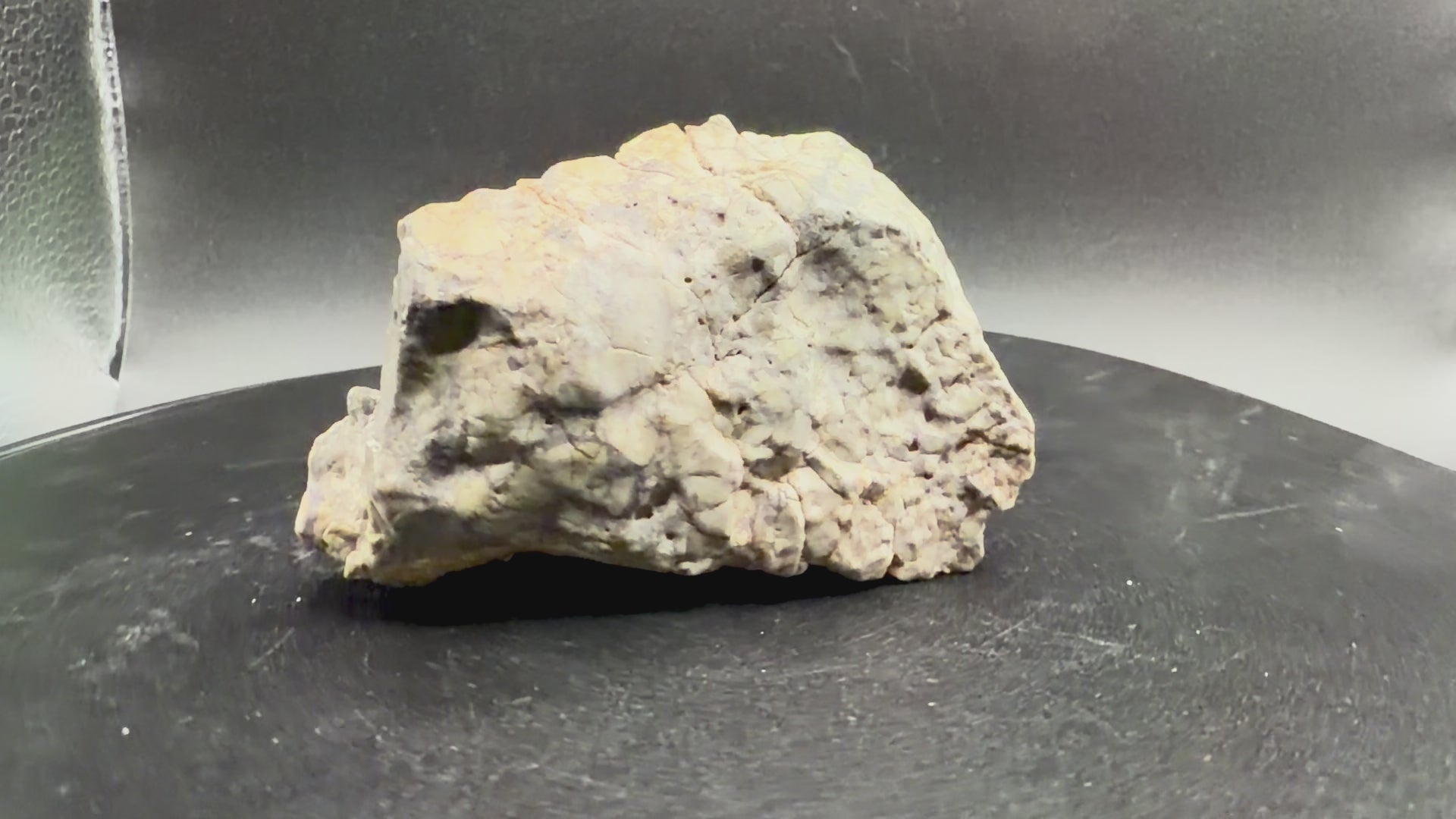 Rotating view of the Adrar 013 lunar melt breccia, 115.15 grams, turning on a display tray