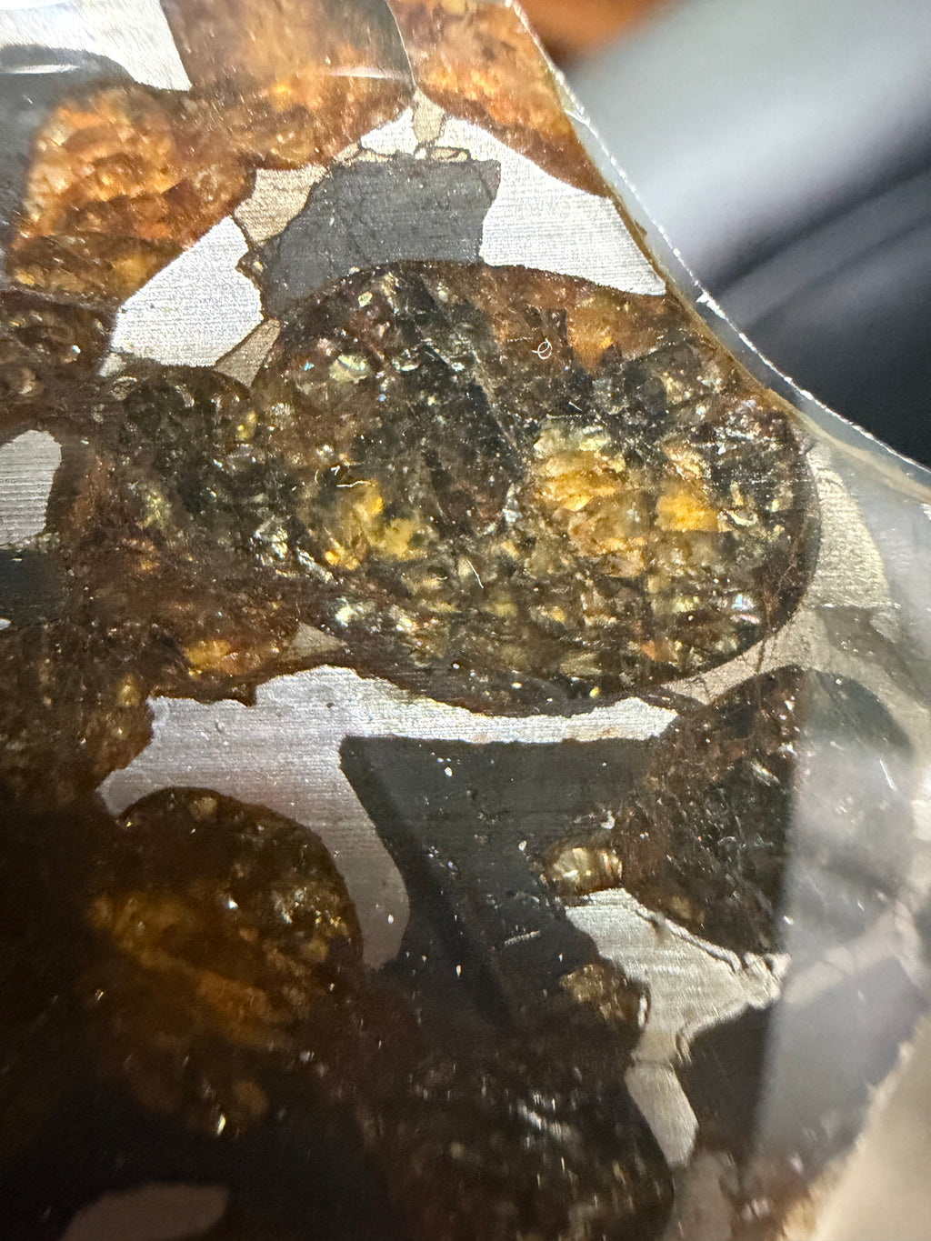 Sericho pallasite meteorite slice, close-up of large olivine crystal cluster showing internal fracture texture and metallic matrix contact